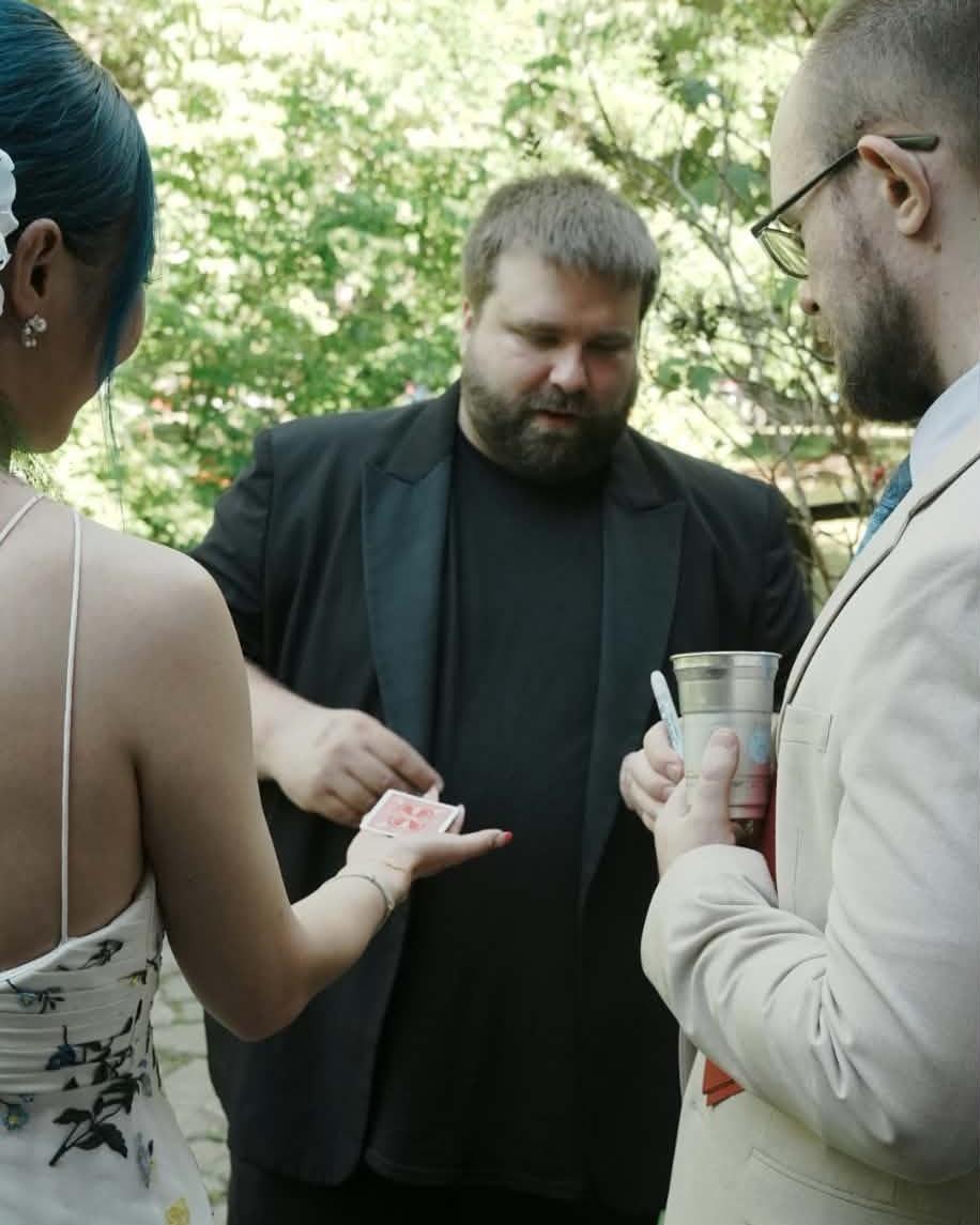 Nate Heater performing close-up card magic for guests at a private event