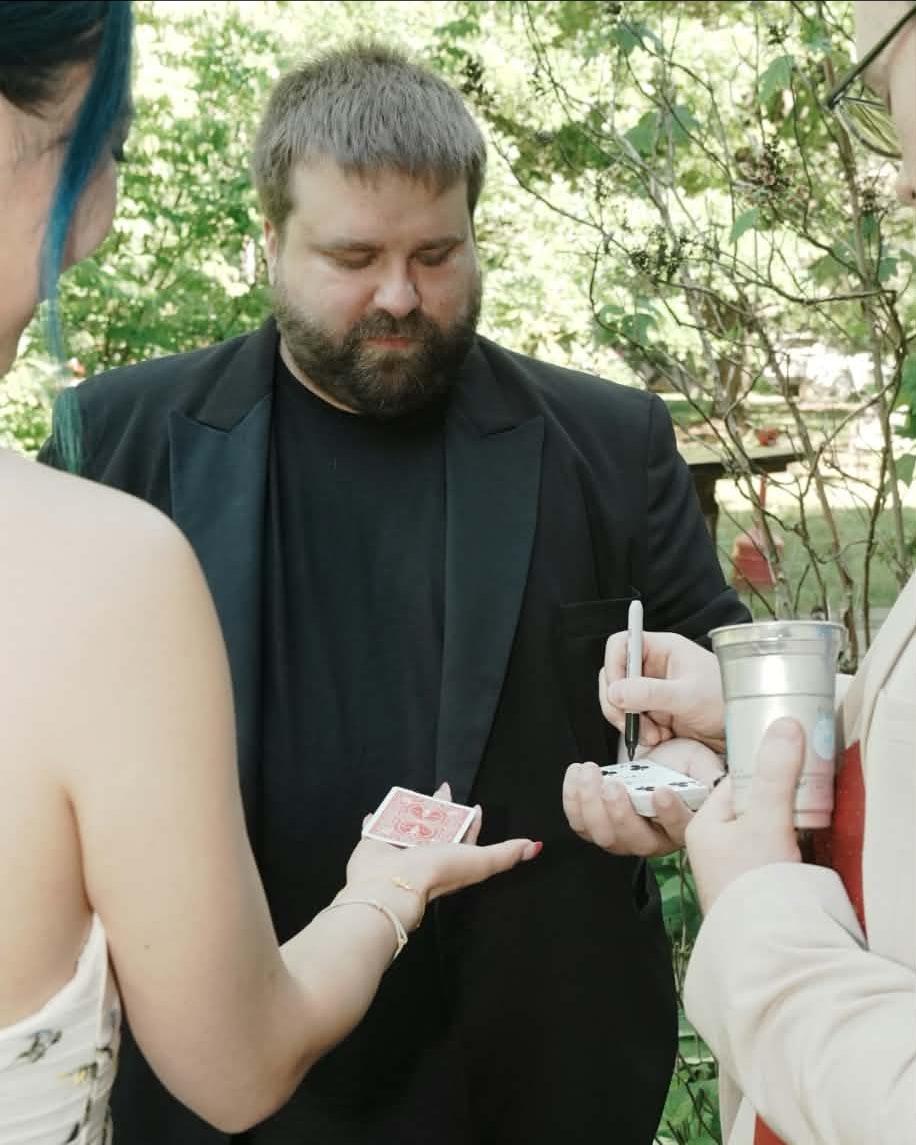 Nate Heater performing walk-around card magic for two guests